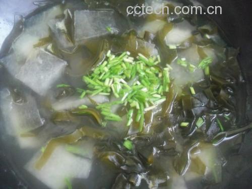 更年期女性日常食养场景:淡干海带丝豆腐汤,突出安全、温和、易操作的家常应用方式 更年期女性厨房场景:青花瓷碗中盛放泡发好的淡干海带丝,搭配豆腐块与枸杞,汤面浮着几滴香油,旁边放着标有“山东荣成淡干海带(Laminaria japonica)”字样的食品级密封罐