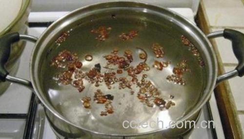 一口不锈钢锅正在炉灶上 simmer 状态下煮着栗子，锅盖半开，热气腾腾，水中栗子清晰可见
