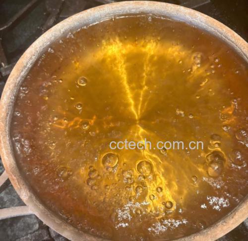 不锈钢小锅中正在熬煮的山楂与姜丝混合液,液体呈琥珀色,表面有细小气泡翻滚,旁边放置计时器和玻璃杯,展示家庭自制场景 山楂姜丝煮制过程