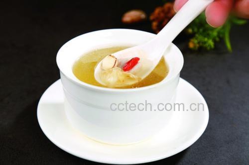 一碗盛满金黄色杏糖水的陶瓷碗,汤体透亮微稠,可见软糯杏肉块和红色枸杞点缀,旁边放一把木勺,背景为木质餐桌与绿植,整体风格温暖自然,突出食物诱人质感 成品杏糖水盛碗图