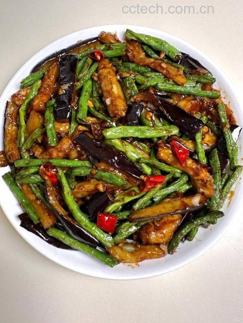 一盘刚出锅的茄子炖扁豆角盛在白色瓷盘中,菜肴色泽红亮,茄子软糯塌陷,扁豆角保持一定韧性,表面覆盖着晶莹的酱汁,旁边点缀几片香菜叶,背景为简约餐桌布置 成品展示图