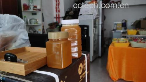 两个小瓶分别装着琥珀色蜂蜜和深棕色陈醋,旁边放着勺子和杯子 蜂蜜与陈醋放在厨房台面上的照片