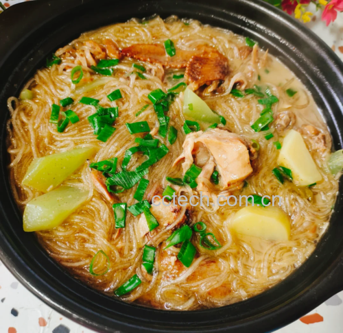 一口黑色铁锅中正在翻炒着翠绿的油菜与半透明的粉条,锅铲翻动间可见酱色汤汁包裹食材,灶台火焰适中,背景为家庭厨房实景 粉条与油菜同锅翻炒场景