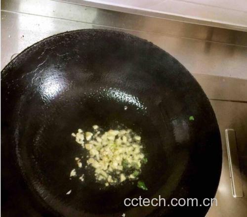 一位厨师正在厨房中用锅翻炒蒜米,锅中有轻微油烟升起,旁边摆放着切好的蔬菜,展现蒜米在日常烹饪中的应用情境 蒜米烹饪场景