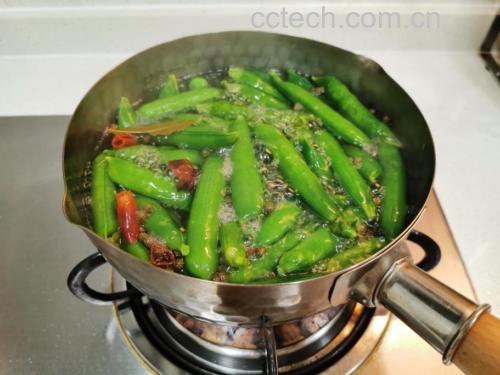 一口中式铁锅中,豌豆尖正在高温翻炒,蒜末散布其间,锅气升腾,体现“镬气十足”的烹饪瞬间 锅中正在翻炒的豌豆尖特写