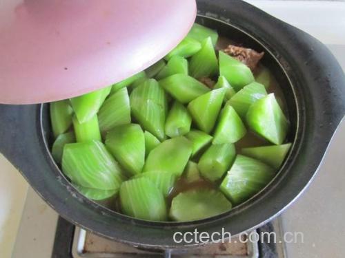 一口不锈钢锅中正在焯烫莴苣片,水已沸腾,莴苣呈鲜绿色,厨师手持漏勺即将捞出,背景为现代厨房环境,光线充足 莴苣焯水过程