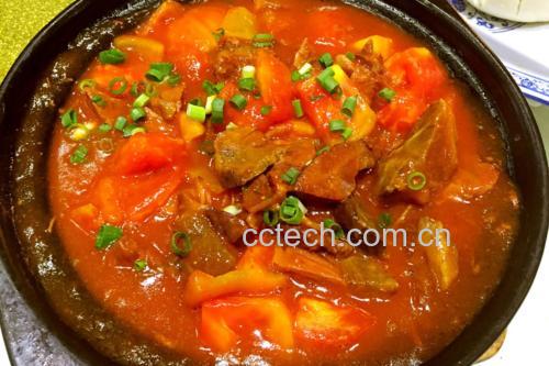 一碗热气腾腾的番茄土豆牛肉盛放在白色瓷盘中,牛肉块饱满,土豆金黄绵软,番茄融入汤汁呈琥珀红色,旁边搭配一碗白米饭,整体色彩温暖诱人 成品展示图