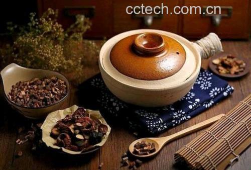 砂锅盛装的深褐色药膳汤品,表面浮有少量油花,可见清晰的鹿茸薄片与鹿鞭段,旁边配有枸杞、黄芪等辅料,背景为木质餐桌与中式餐具,体现家庭养生场景 鹿茸鹿鞭炖汤成品图