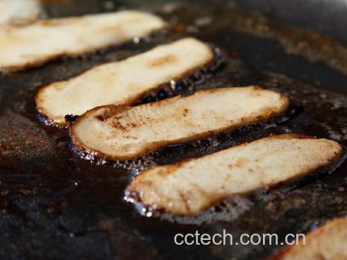 厨房锅具中正在翻炒的东北松蘑与松花菜，锅内食材色泽油亮，松蘑呈深褐色，松花菜为浅黄色，热气腾腾，展现烹饪中途的状态