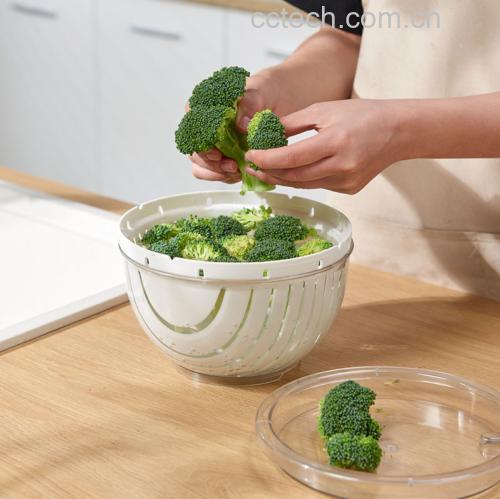 一名厨师正在厨房中将松花菜掰成小朵,并放入透明玻璃盆中的淡盐水中浸泡,背景有流动水龙头和沥水篮,展示完整的清洗流程 松花菜清洗过程特写