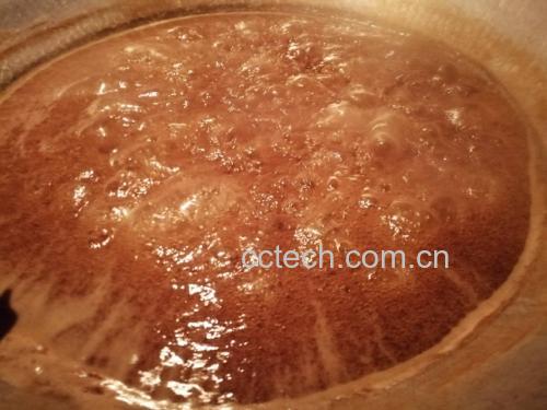 糖浆在锅中加热,呈现出淡淡的琥珀色,锅边有细密气泡冒出 糖浆正在锅中熬煮呈琥珀色