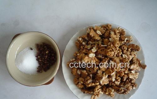 一盘刚出锅的椒盐核桃仁,颜色金黄酥脆,表面均匀裹着细盐粒、花椒粉和白芝麻,置于白色陶瓷碟中,背景虚化的竹筷暗示可即食 椒盐核桃成品摆盘