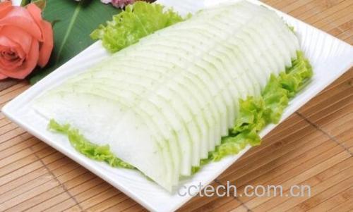 白色瓷盘中盛放着刚出锅的炒冬瓜,冬瓜片呈半透明翡翠绿色,点缀着金黄蒜片和红色辣椒圈,葱段翠绿,整体干爽无多余汤汁,旁边摆放竹筷一双,背景为浅色餐桌布 成品装盘效果展示
