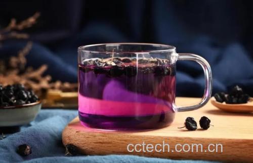 图片说明:一杯已经冲泡完成的黑枸杞雪菊茶,颜色呈淡紫色,清澈透亮,搭配木质托盘营造出自然健康的氛围 成品黑枸杞雪菊茶特写图