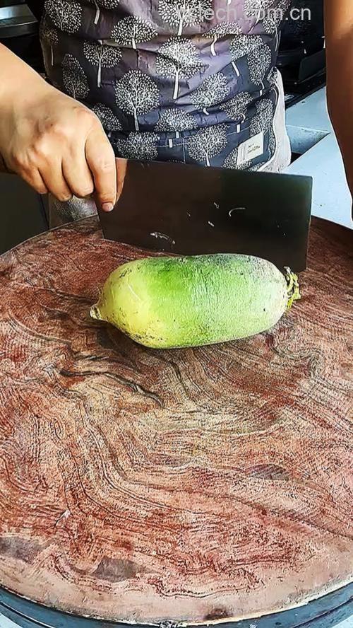 一名厨师正在厨房中用刀在软籽石榴顶部划圈切割,石榴放置在白色砧板上,背景整洁明亮,光线自然 图片描述