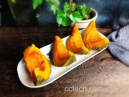 一张木制餐桌上摆放三款创意贝贝板栗南瓜料理:左侧是装在南瓜壳内的芝士焗蛋,中间是一杯橙黄色的南瓜奶昔配吸管,右侧是一碗金黄色的南瓜小米粥撒有枸杞点缀,整体光线柔和温馨,体现家庭美食氛围 创意南瓜料理拼盘展示