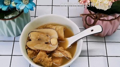 一碗热气腾腾的浅棕色汤品,内含泡发后柔韧的米白色鹿茸菇团块与深绿色海带片,汤面浮有少量油花,旁边配有筷子和瓷勺,背景为简约中式餐桌,营造温馨家常氛围 干鹿茸菇海带排骨汤成品图