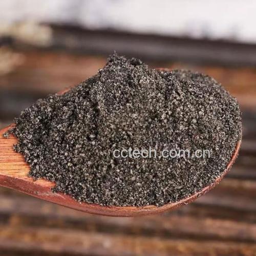 一位女性在厨房使用石磨将焙炒后的黑芝麻研磨成细腻黑色粉末,旁边摆放玻璃罐用于储存,桌上有芝麻、标签纸和量勺,自然光线明亮,体现健康生活方式 家庭自制黑芝麻粉场景图