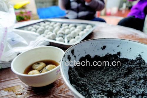 一位女性在厨房灶台前煮黑芝麻汤圆,锅中汤圆浮起,水面微沸,旁边有切好的生姜片和一小碗红糖,展现健康烹饪场景 一位中年女性正在厨房用小火煮锅中的黑芝麻汤圆,锅边放置生姜片和红糖