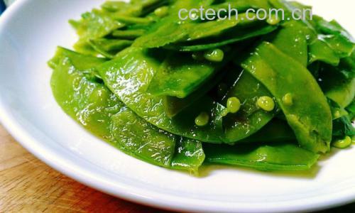 新鲜翠绿的荷兰豆整齐排列在白色瓷盘中,背景为浅色厨房台面,光线柔和自然,突出食材的新鲜度与色泽 荷兰豆特写