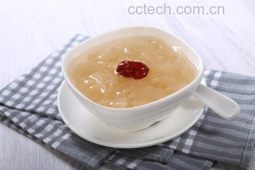 一碗刚出锅的浓稠银耳羹,呈浅琥珀色,盛放在白色陶瓷碗中,汤体饱满有光泽,用瓷勺舀起时可见细密拉丝,周围点缀几颗红枣和枸杞,背景虚化,突出食物质感与温润氛围 成品浓稠银耳羹盛入瓷碗,表面泛着光泽,勺子舀起时可见明显拉丝现象