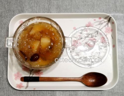 一碗晶莹剔透的香梨银耳羹盛在白色瓷碗中,银耳胶质丰富呈半透明状,香梨块清晰可见,点缀着红色红枣,汤体微微反光,背景为简约中式餐桌风格 香梨银耳羹盛装特写
