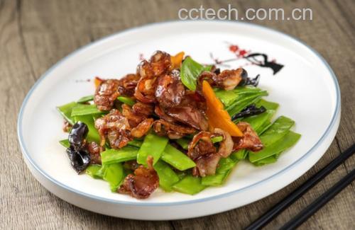 一盘刚出锅的荷兰豆炒腊肉盛放在浅灰色陶瓷盘中,腊肉片红润油亮,荷兰豆翠绿挺括,整体色泽鲜明,表面略带光泽,背景为简约中式餐桌布置 荷兰豆炒腊肉成品图