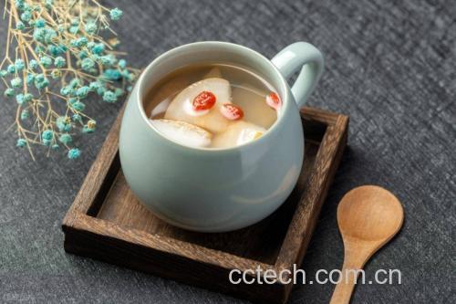 一碗正在炖煮的冰糖香梨汤,陶瓷盅内香梨块与冰糖共煮,蒸汽袅袅升起,周围摆放新鲜香梨和枸杞,体现家庭养生食疗场景 香梨烹饪场景