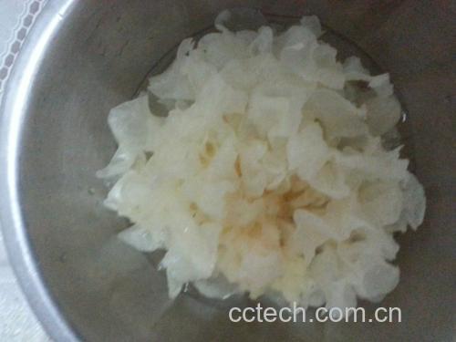 三组透明玻璃碗横向排列,分别展示:第一碗为干银耳原样;第二碗为冷水浸泡4小时后的泡发状态,银耳舒展成菊花状,水质清澈微带胶质感;第三碗为炖煮30分钟后的银耳羹,汤体浓稠可拉丝,背景为厨房台面,配有量杯和勺子 银耳泡发展示图