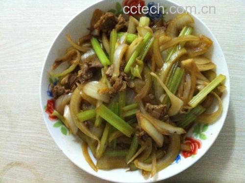 一盘色泽鲜亮的清炒山芹牛肉,山芹翠绿,牛肉棕红,红椒点缀其间,盛放在白色瓷盘中,背景为家庭厨房灶台,展现家常美食氛围 清炒山芹牛肉成品图