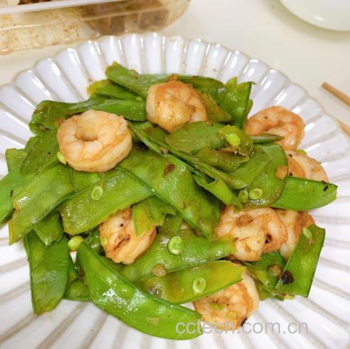 中式炒锅中正在高温翻炒荷兰豆与虾仁,食材在空中翻飞,锅气升腾,蒜片清晰可见,虾仁呈粉白色,荷兰豆碧绿,体现‘镬气十足’的烹饪状态 锅中爆炒动态瞬间