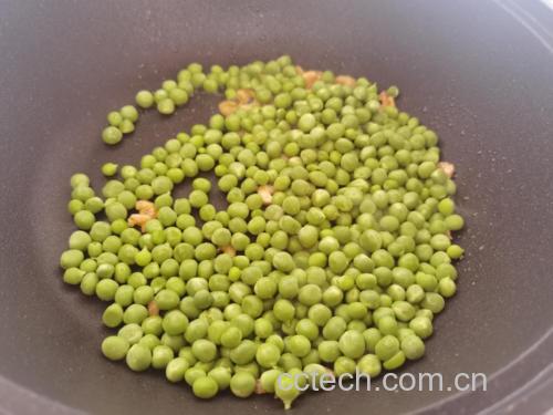 中式炒锅中正在翻炒青豌豆与玉米粒,锅内食材呈现金黄与翠绿交织状态,蒜末清晰可见,灶火旺盛,体现‘锅气十足’的烹饪场景 青豌豆炒玉米烹饪过程图