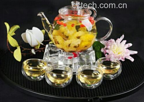 透明玻璃杯中正在冲泡杭白菊茶,热水倒入瞬间花瓣舒展,花朵缓缓下沉,水中泛起淡黄色茶汤,背景为厨房台面,左侧放置陶瓷茶叶罐,展现真实冲泡场景 杭白菊茶冲泡过程