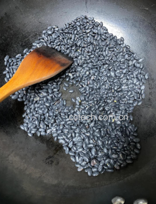 一位亚洲女性在厨房中准备黑豆红豆食材，面带微笑，动作自然