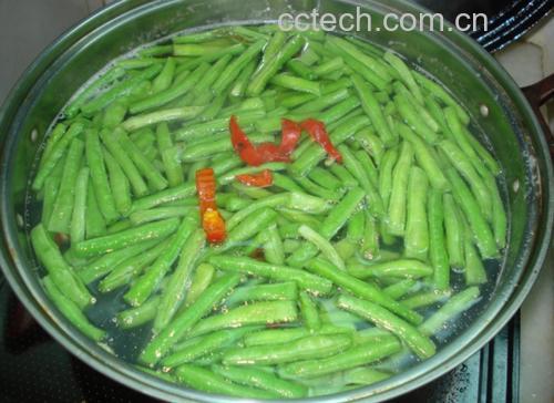 一位厨师正在家庭厨房中用铁锅翻炒豆角丝,锅中豆角呈金绿色,略有焦边,配以蒜片和红椒丝,动作流畅,体现‘锅气十足’的中式快炒技法,背景整洁,突出健康烹饪场景 家庭厨房炒菜场景