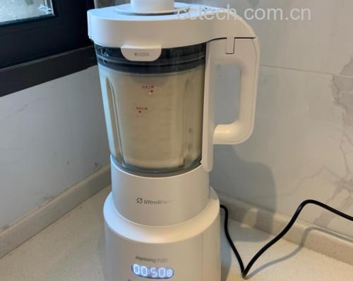 厨房台面上摆放一台白色破壁机,机器内可见深褐色黑豆浆正在高速旋转搅打,旁边放着一碗泡发好的黑豆、量杯和水壶,背景整洁明亮,体现家庭健康烹饪氛围 正在用破壁机打黑豆豆浆的场景