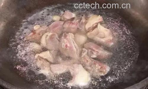 正在用铲子翻炒锅中的鸡腿块,鸡块呈酱褐色,大葱段清晰可见,锅中蒸汽升腾,灶火旺盛,体现大火快炒的场景 大葱爆炒鸡腿烹饪过程