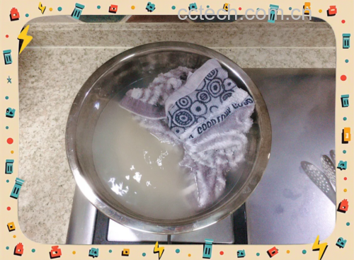 一名厨师戴着手套,正在将一盘刚从沸水中捞出的透明藕片倒入一个盛有大量冰块和水的不锈钢盆中,水面泛起白烟,显示温差剧烈,操作台整洁,背景为专业厨房环境 厨师正在将焯水后的藕片倒入装满冰块的盆中进行冷却处理