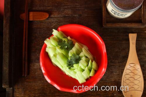 一张干净的白色餐桌上摆放着一份刚出锅的by爆炒小黄瓜,菜肴呈翠绿色,点缀着红色干辣椒和金黄蒜片,旁边配有一双竹筷和一小碗白米饭,自然光线从左侧照射,整体画面温馨诱人 成品菜肴全景展示