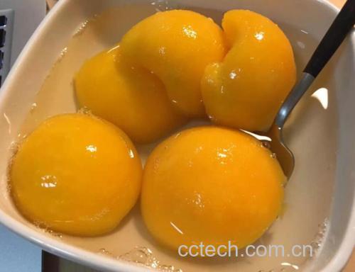 一碗晶莹剔透的黄桃糖水摆放在浅灰色餐盘中,黄桃果肉完整金黄,汤汁清澈微甜,旁边配有透明玻璃罐装的黄桃罐头,标签手写‘自制黄桃罐头’,背景为夏日餐桌布景,阳光洒落 黄桃成品展示
