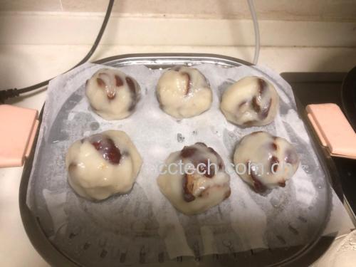 多个圆形面团整齐排列在竹编蒸笼里,每个面团顶部嵌有一颗去核骏枣,背景为传统农家厨房环境,木质案板与陶罐点缀其间 山东枣饽饽生坯摆放于竹制蒸笼中