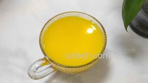 一位手部特写正端着一杯透明玻璃杯装的金桔柠檬饮品,杯中有清晰可见的金桔块和柠檬片,冰块晶莹,液体呈淡黄色,背景为浅色木桌与绿植 手握透明饮品杯展示金桔柠檬茶