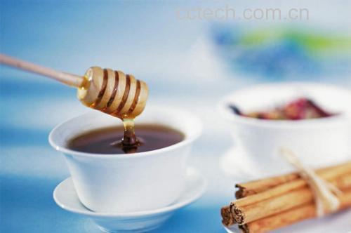 一位年轻女性坐在书桌前,面前放着一杯冒着热气的金桔蜜饯茶,玻璃杯中浸泡着两颗饱满的蜜饯,旁边笔记本打开记录‘护嗓小妙招’,窗外阳光洒入,营造温馨健康生活氛围 金桔蜜饯日常食用场景