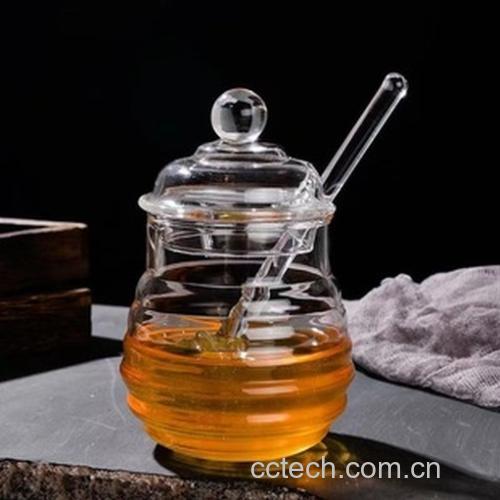 透明玻璃罐中装有金黄色的金桔与柠檬块交替叠放,表面被浓稠的天然蜂蜜完全覆盖,液体微微透光,旁边摆放一勺正在舀取的状态,背景为厨房木质台面 金桔柠檬蜂蜜腌制品特写