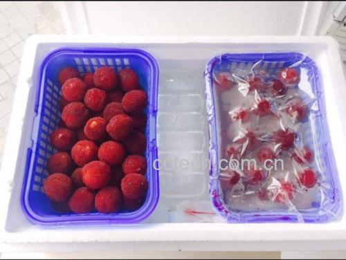 东魁杨梅清洗过程 一位女性正在用盐水浸泡东魁杨梅进行清洗,桌上摆放着新鲜采摘的杨梅果实,背景为厨房环境,体现家庭健康饮食场景