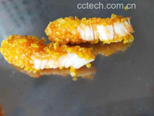 一只手正将腌好的鸡腿肉按压进浅盘中的金黄色面包糠里,另一只手扶稳肉片,周围散落着蛋液碗、淀粉碟和剩余面包糠,灯光聚焦在鸡肉表面,清晰展现面包糠紧密贴合的状态 裹粉过程特写