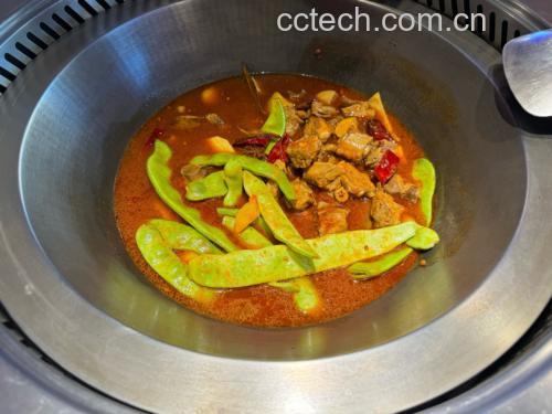 一大盘热气腾腾的白不老豆角焖面盛放在白色瓷盘中,面条油亮有光泽,豆角青白相间,夹杂着五花肉片,整体色泽诱人,旁边配有筷子和小碗,呈现最终上桌效果 成品白不老豆角焖面