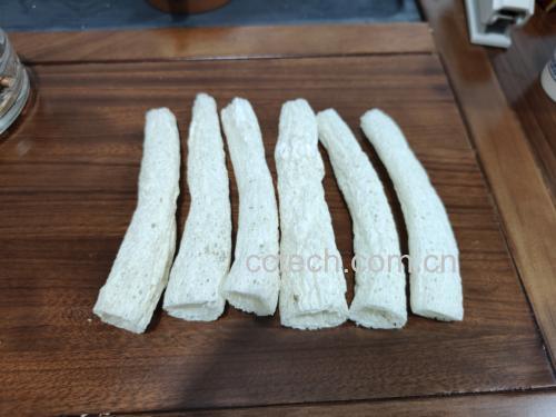 一碗透明玻璃盆中浸泡着数朵乳白色长裙竹荪,菌裙舒展如蕾丝裙摆,水中可见细小气泡附着在表面,旁边摆放着几片生姜和一瓶白醋,背景为厨房台面木质纹理 泡发中的长裙竹荪特写