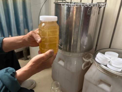 制作冰蜂蜜水的过程:玻璃杯中倒入蜂蜜,旁边是冰块和柠檬片,背景为厨房环境 冰蜂蜜水制作过程