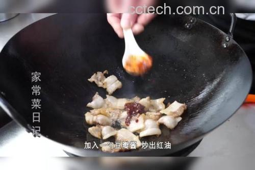 中式炒锅中正在烹制回锅肉,铲子翻动间可见红亮的豆瓣酱包裹着肉片和青蒜。灶台旁摆放一瓶打开的传统豆瓣酱,标签清晰可见‘蚕豆’为主要原料。展现豆瓣酱在日常饮食中的真实应用场景 家庭厨房中使用豆瓣酱烹饪回锅肉的特写镜头